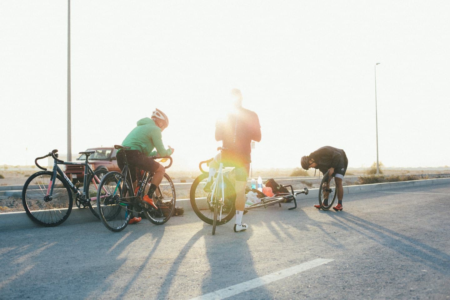 Ciclisti che riposano sul ciglio della strada con biciclette e borracce.